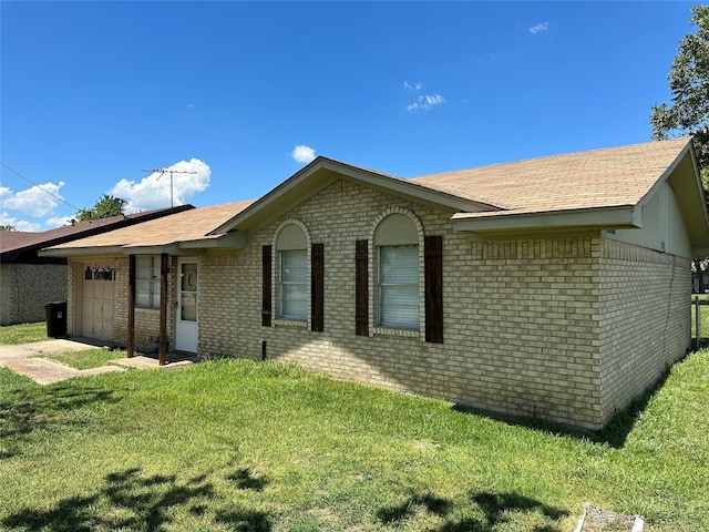 ranch-style home with a garage, driveway, brick siding, and a front yard