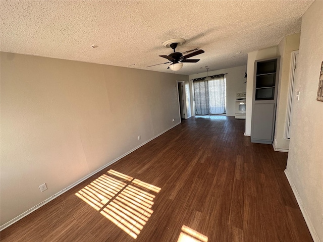 spare room featuring a textured ceiling, wood finished floors, a ceiling fan, and baseboards