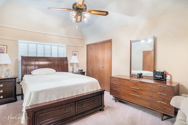 bedroom with lofted ceiling, a closet, a ceiling fan, and light colored carpet