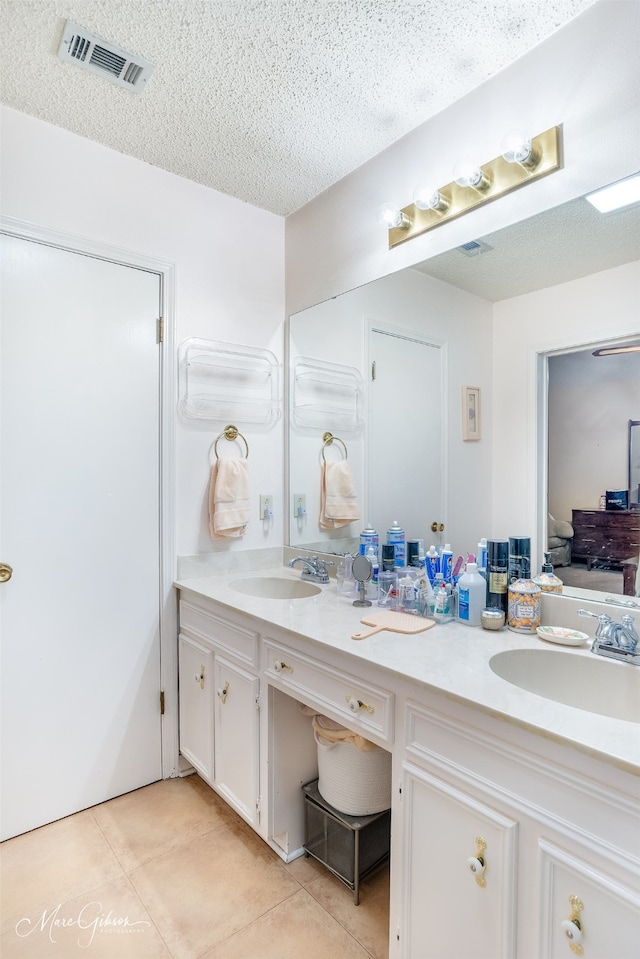 ensuite bathroom featuring tile patterned flooring, visible vents, and a sink