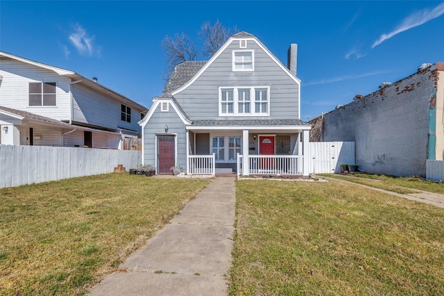 view of front of home with covered porch, a front lawn, a shingled roof, and fence