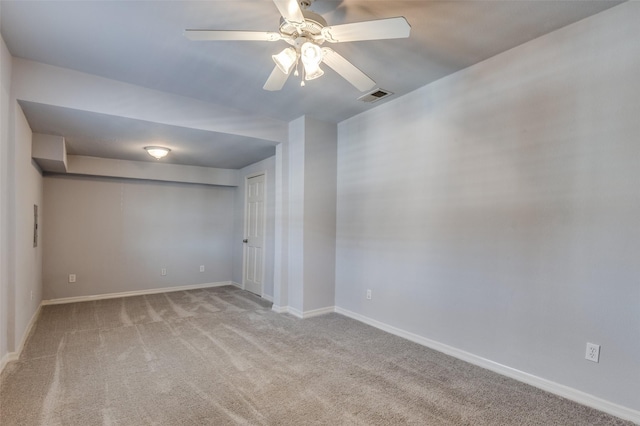 carpeted spare room featuring visible vents, ceiling fan, and baseboards