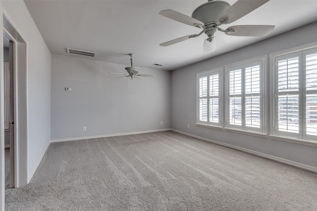 empty room featuring carpet floors, baseboards, visible vents, and a ceiling fan