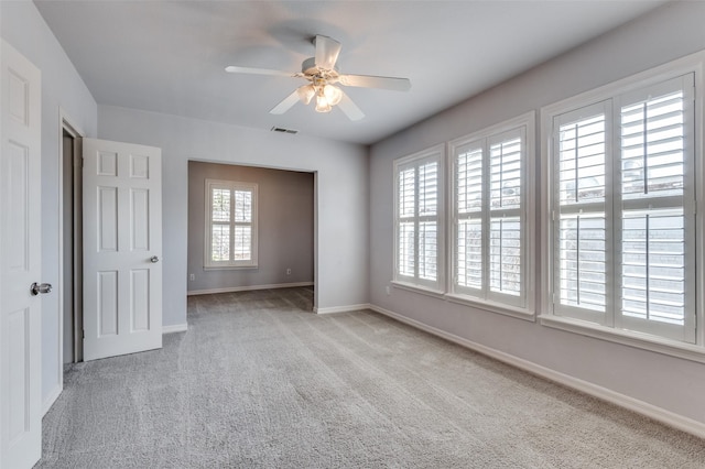 empty room with a ceiling fan, carpet, visible vents, and baseboards