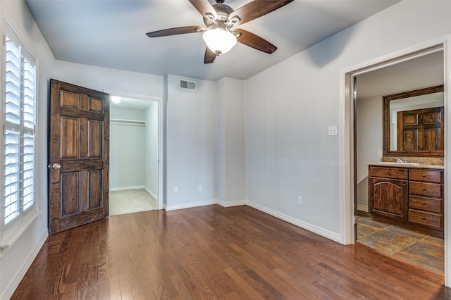 bedroom with a walk in closet, dark wood-style flooring, visible vents, and multiple windows