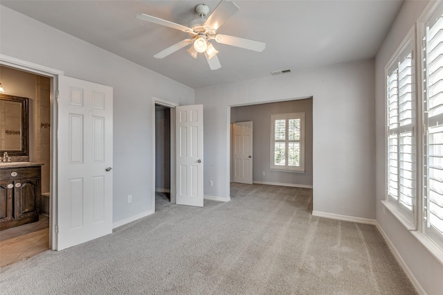 unfurnished bedroom with a ceiling fan, light colored carpet, visible vents, and baseboards