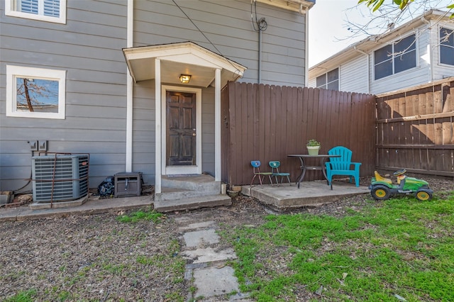 doorway to property with a patio area, fence, and central AC unit