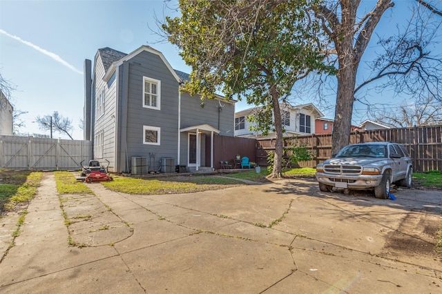 back of property with central AC unit and a fenced backyard