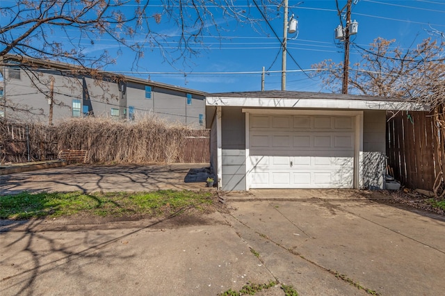 detached garage featuring driveway and fence