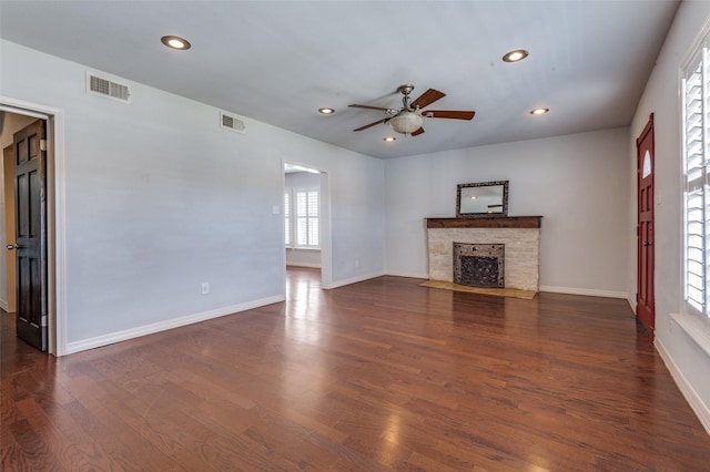 unfurnished living room with dark wood-style flooring, recessed lighting, visible vents, a stone fireplace, and baseboards