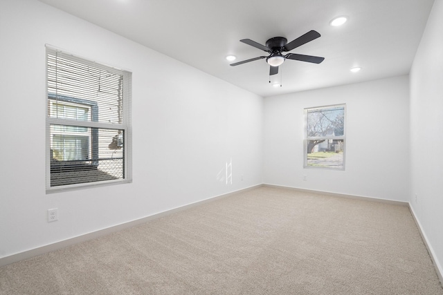 empty room featuring light carpet, ceiling fan, recessed lighting, and baseboards