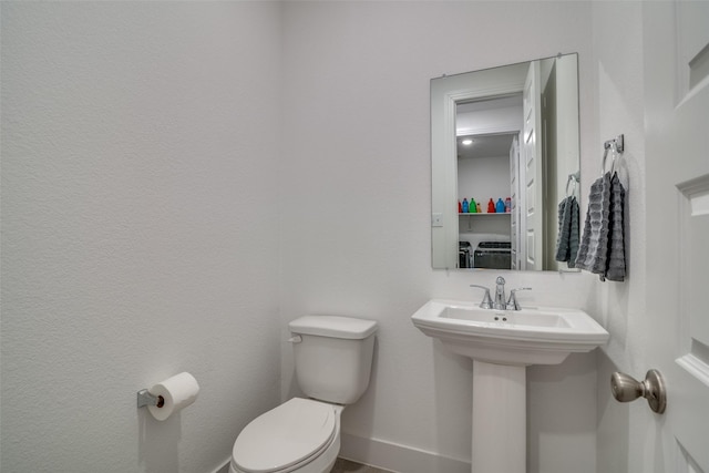 bathroom featuring a sink, toilet, and baseboards