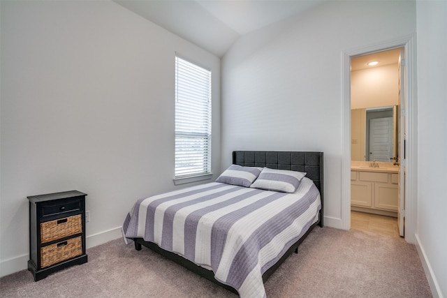 bedroom with light carpet, baseboards, connected bathroom, and lofted ceiling