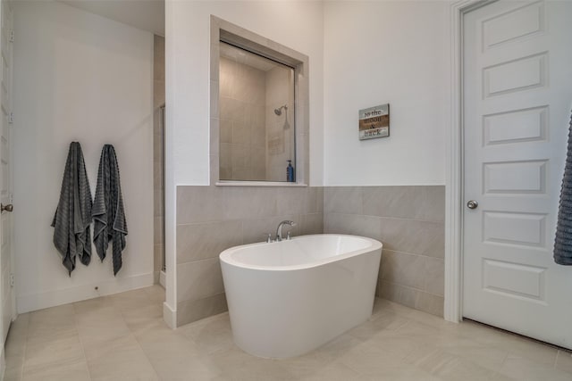 bathroom with a freestanding tub, a tile shower, tile walls, and tile patterned floors