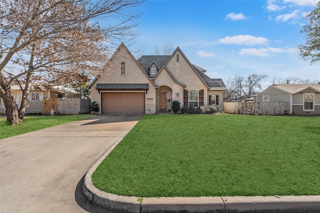 french country inspired facade with a garage, fence, driveway, and a front lawn