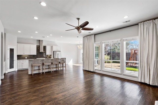 living room with dark wood finished floors, recessed lighting, visible vents, baseboards, and ceiling fan with notable chandelier