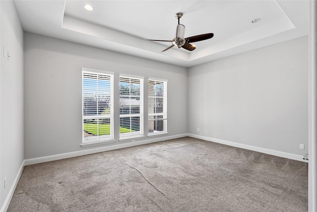 spare room featuring a ceiling fan, a raised ceiling, and baseboards