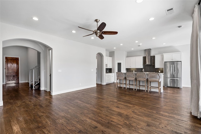 living area with visible vents, arched walkways, dark wood-style floors, and ceiling fan