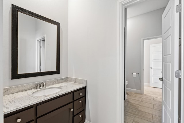 bathroom featuring toilet, baseboards, vanity, and wood tiled floor