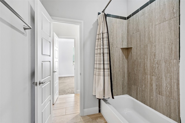 bathroom with shower / bath combo and baseboards