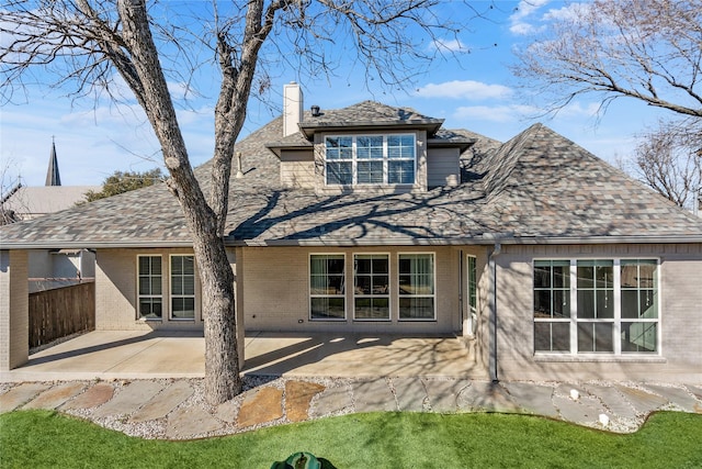 back of property with brick siding, a patio, a chimney, and roof with shingles