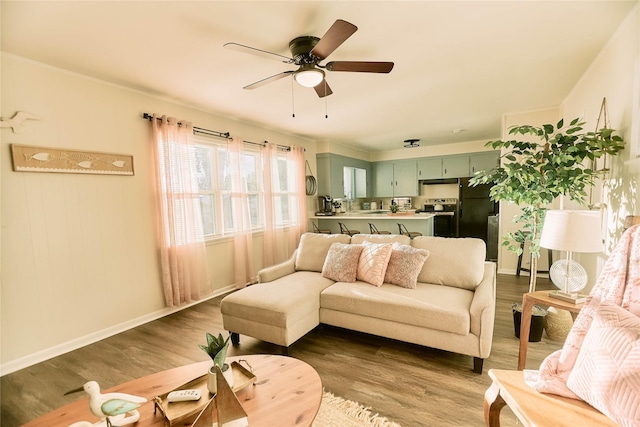 living area with dark wood-style floors, ceiling fan, and baseboards