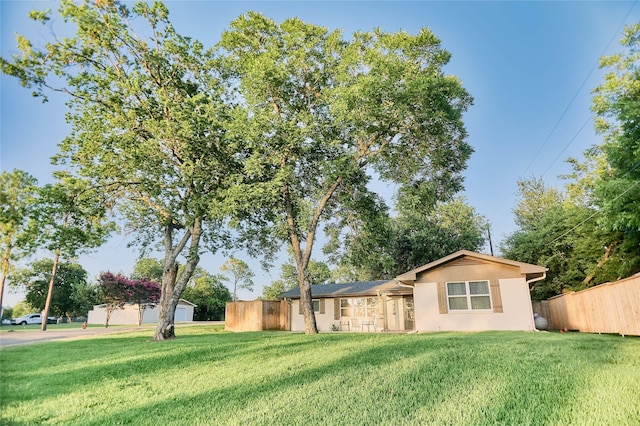 exterior space with fence, a front lawn, and stucco siding