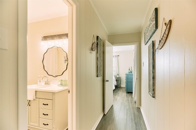 hallway with ornamental molding, baseboards, and wood finished floors