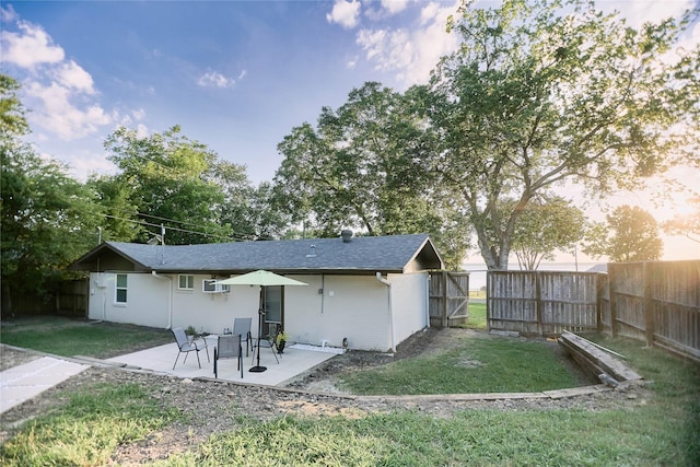 rear view of property featuring a patio, a lawn, fence, and a gate