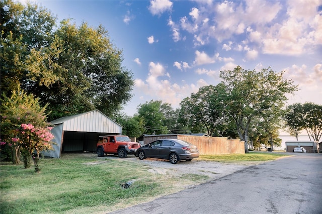 view of parking / parking lot featuring a garage, a pole building, and fence