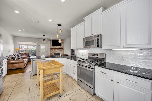 kitchen featuring stainless steel appliances, a peninsula, open floor plan, backsplash, and dark countertops