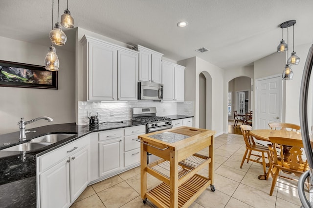 kitchen with visible vents, decorative backsplash, arched walkways, appliances with stainless steel finishes, and a sink