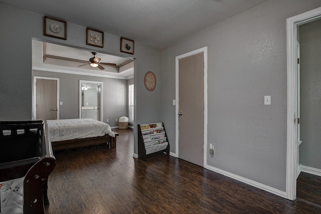 bedroom featuring a raised ceiling, wood finished floors, connected bathroom, and baseboards