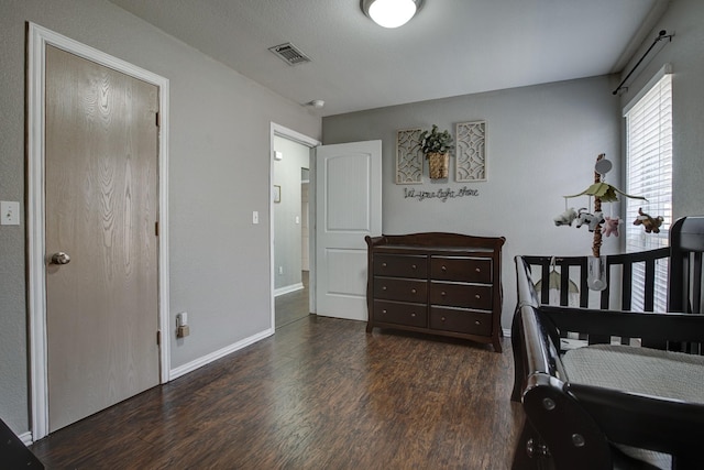 bedroom featuring wood finished floors, visible vents, and baseboards