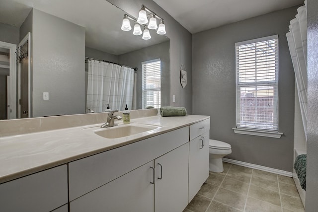 bathroom featuring toilet, plenty of natural light, baseboards, and vanity