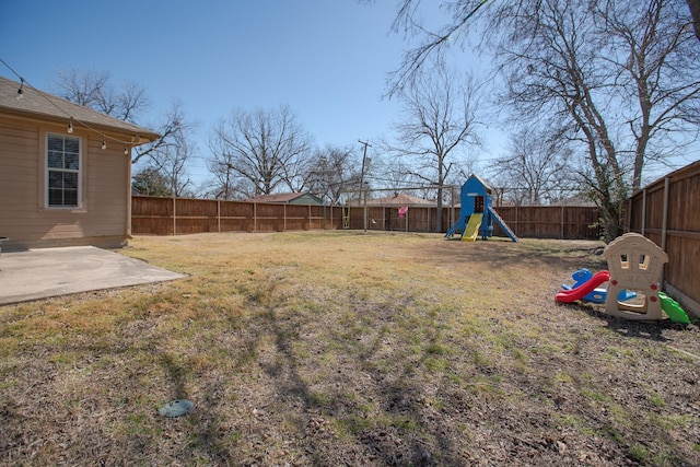 view of yard featuring a patio area, a playground, and a fenced backyard