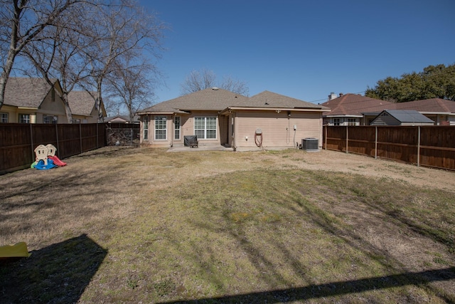 back of property featuring central AC, a yard, and a fenced backyard