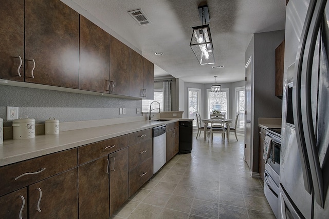 kitchen with dark brown cabinetry, a sink, visible vents, light countertops, and appliances with stainless steel finishes