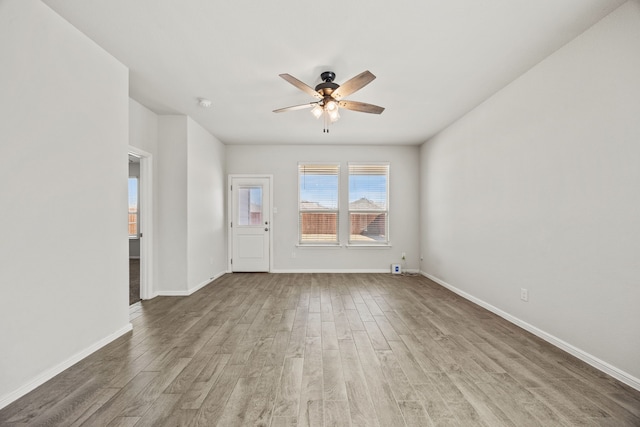 unfurnished living room with ceiling fan, baseboards, and wood finished floors