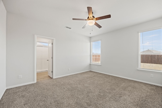 carpeted spare room featuring ceiling fan, visible vents, and baseboards