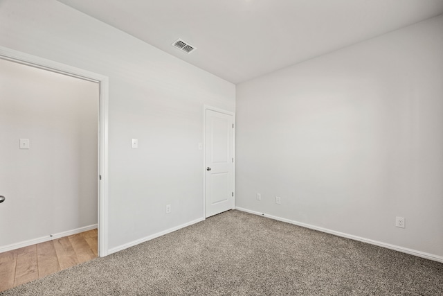 carpeted spare room featuring baseboards and visible vents