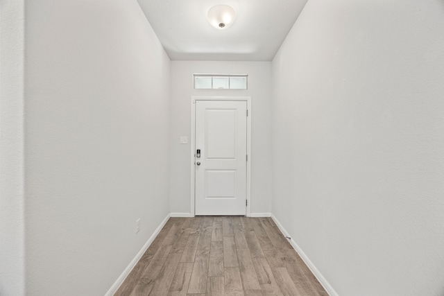 doorway to outside featuring baseboards and wood finished floors