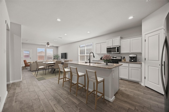 kitchen featuring stainless steel appliances, dark wood finished floors, white cabinetry, and a sink