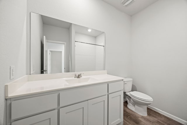 bathroom featuring visible vents, baseboards, toilet, wood finished floors, and vanity