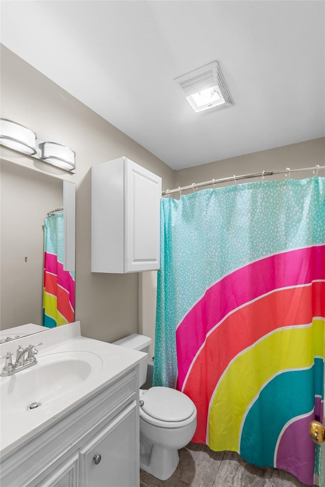 bathroom featuring curtained shower, visible vents, vanity, and toilet