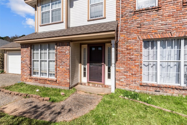 property entrance featuring a garage, brick siding, and a shingled roof