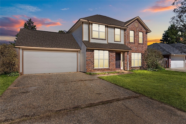 traditional home featuring brick siding, a yard, a shingled roof, an attached garage, and driveway