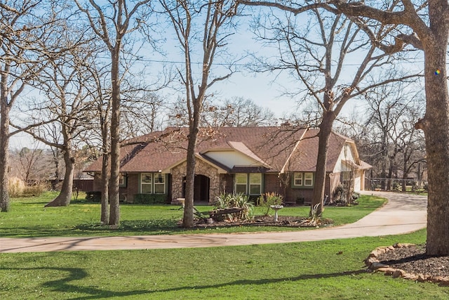 view of front of property featuring a shingled roof, stone siding, brick siding, and a front lawn