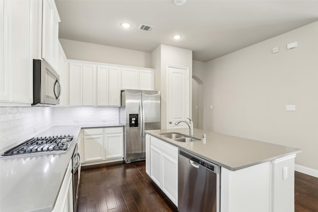 kitchen with a center island with sink, dark wood-style floors, a sink, stainless steel appliances, and backsplash