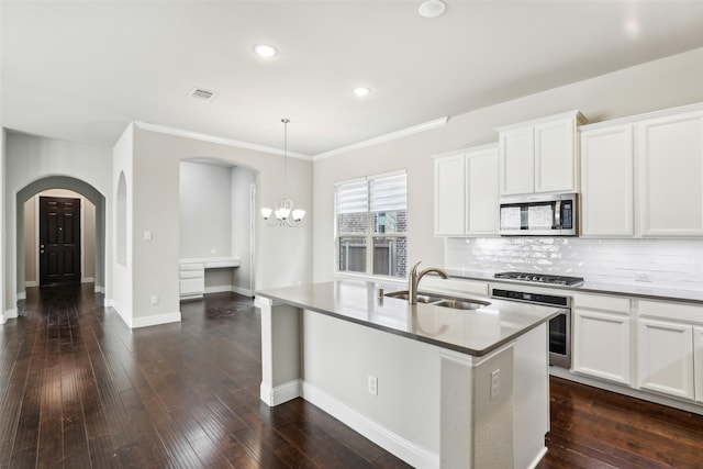 kitchen with dark wood-style floors, arched walkways, stainless steel appliances, and a sink